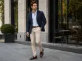Mężczyzna w granatowej marynarce, błękitnej koszuli i beżowych spodniach prezentuje styl smart casual.