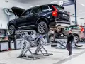 Mekaniker arbetar med en svart Volvo på en billyft i en auktoriserad verkstad.