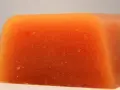 Bloque naranja de carne de membrillo, con textura granulada y bordes redondeados.