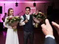 Para młoda z bukietami kwiatów, mężczyzna trzyma mikrofon.