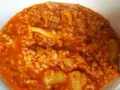 Arroz caldoso con trozos de marisco y verduras en salsa rojiza.