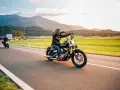 Motociclista in viaggio su una strada panoramica, un'atmosfera da European Bike Week con montagne sullo sfondo.