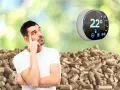 Un homme réfléchit devant un tas de granulés de bois, un thermostat intelligent Netatmo affiche 22°.