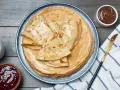 Pile de crêpes dorées, parfaites pour une recette pâte à crêpes. Accompagnées de confiture, pâte à tartiner et verre de lait.
