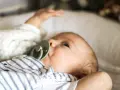 Uroczy noworodek z niebieskimi oczami i smoczkiem. Sprawdzam temperaturę noworodka na czole, by upewnić się, że jest mu komfortowo.