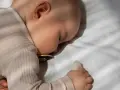 Bambino dorme sereno, forse grazie alla melatonina per bambini iperattivi, con ciuccio e peluche.