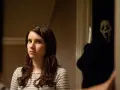 Dziewczyna z "Krzyk 4 obsada" wpatruje się w Ghostface'a, który czai się w cieniu z nożem.