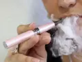 Persona exhala vapor de un cigarrillo electrónico rosa. ¿Qué es peor el vaper o el tabaco?