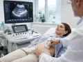 Lekarz wykonuje usg jamy brzusznej pacjentce. Na ekranie widoczny obraz narządów.