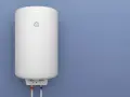 Termo eléctrico no calienta, piloto encendido. El calentador blanco está colgado en una pared azul, con tuberías rojas y azules debajo.