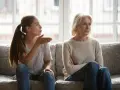 Junge Frau gestikuliert wütend, während ihre Mutter abgewandt sitzt. Es scheint, als ob meine Tochter mich hasst.