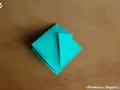 Krok 15 instrukcji, jak zrobić kwadrat z papieru. Turkusowa origami na drewnianym tle.