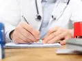 Lekarz pisze receptę, zastanawiając się, czy do neurologa potrzebne jest skierowanie.