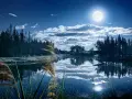 Paysage nocturne féerique, lac paisible reflétant la lune et les nuages. Une retouche photo paysage Photoshop qui sublime la nature.