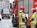 Dwóch strażaków w hełmach i mundurach stoi przy wozie strażackim. W tle wóz saperski. Starszy ogniomistrz zarobki to marzenie wielu, ale oni służą.