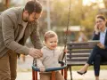 Ein Vater schaukelt sein Kind. Im Hintergrund telefoniert eine Frau. Die Frage, an welchen Kosten sich der Vater beteiligen muss, bleibt offen.