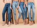 Cztery kobiety w różnych odcieniach jeansów siedzą na stołkach. Denim to materiał, który nigdy nie wychodzi z mody.