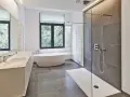 Salle de bain moderne avec douche à l'italienne aux galets hydrofuges, baignoire îlot et double vasque.
