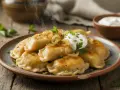 Dampfende Pierogi Ruskie auf einem Teller, garniert mit Zwiebeln, Petersilie und einem Klecks Sauerrahm.