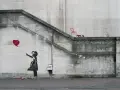 La célèbre œuvre de Banksy, "Girl with Balloon", sur un mur de pierre. Une petite fille lâche un ballon en forme de cœur rouge.