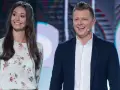 Uśmiechnięta para na scenie, gdzie nagrania programu telewizyjnego. Ona w kwiecistej sukience, on w marynarce.