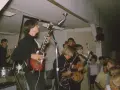 Un jeune Alice Cooper et son groupe jouent sur scène, entourés de fans.