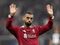 Mohamed Salah w czerwonej koszulce Liverpoolu, z uniesionymi dłońmi, pozdrawia kibiców. Widać logo klubu i sponsora.