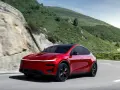 Czerwony Tesla Model Y Performance na krętej drodze w górach.