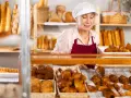 Starsza pani piekarz z uśmiechem układa świeże croissanty. To ulga dla pracujących seniorów, którzy wciąż mają pasję.