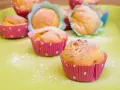 Leckere Muffins ohne Ei, bestäubt mit Puderzucker, in bunten Papierförmchen auf einer hellgrünen Platte.