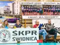 Na banerze widnieje drużyna SKPR Świdnica. Dwie kobiety siedzą za stołem z piłką ręczną.