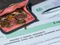 Portmonetka z monetami leży obok formularza ZUS Z-15B, który dotyczy wniosku o zasiłek opiekuńczy.