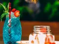 Orzeźwiający, niebieski drink z palemką, ozdobiony truskawką i miętą. Idealny na letnie popołudnie.