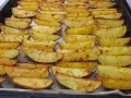 Des pommes de terre rôties au four croustillantes, dorées et assaisonnées, disposées sur une plaque de cuisson.