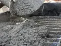 Świeży beton z kruszywem, idealny jako jaki beton pod obrzeża, wylewany z maszyny na ruszt.
