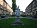 Pomnik w stylu socrealizmu na tle bloków mieszkalnych.