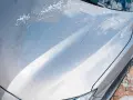 Krople wody i piany na masce srebrnego auta. Czy po woskowaniu płukać auto? Tak, aby uzyskać idealny połysk.