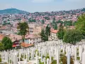 Widok na cmentarz z białymi nagrobkami i panoramę Sarajewa. Warto zobaczyć to miejsce, by poczuć historię miasta.