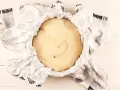 Masa de pan de patata cruda, cubierta con un paño blanco con estampado floral gris, lista para levar.