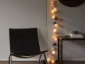 En svart läderfåtölj står bredvid ett bord med böcker och en skål. En ljusslinga med runda ljus ger en mysig inredning med ljusslingor.