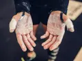Mains de sportif couvertes de magnésie, prêtes à saisir la barre. Une corne sur la main témoigne des efforts.