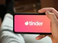 Dłoń trzyma smartfon z otwartą aplikacją do randkowania Tinder.