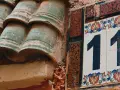 Numerologiczna 11 mężczyzna, jak liczba 11 na ozdobnej tabliczce obok zielonych dachówek, symbolizuje intuicję i duchowość.