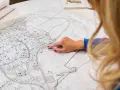 Kobieta z rudymi paznokciami wskazuje palcem na mapę. Plan miasta, z zaznaczonymi ulicami i budynkami, sugeruje analizę terenu pod kątem jego **użytku ba**.