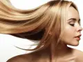 Blond włosy falujące na wietrze, lśniące jak po płukance octowej. Delikatny profil kobiety z zamkniętymi oczami.