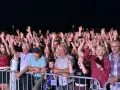 Tłum ludzi na koncercie, wszyscy z podniesionymi rękami, cieszą się muzyką. Widać uśmiechnięte twarze, a niektórzy nagrywają telefonami. To z pewnością niezapomniane **baciary utwory**!