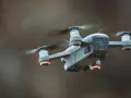 A drone hovers mid-air, its propellers a blur. Red anti-collision lights glow on its arms, ensuring safe flight.