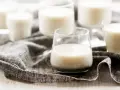 Plusieurs verres remplis de kéfir crémeux, posés sur une serviette grise.
