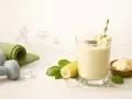 Pyszny koktajl bananowy z nasionami chia, idealny po treningu. Obok leżą hantle i mata do ćwiczeń.