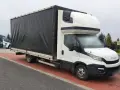 Biały bus Iveco z czarnym plandeką, ładowność 1,5 tony, stoi na czerwonej kostce brukowej.